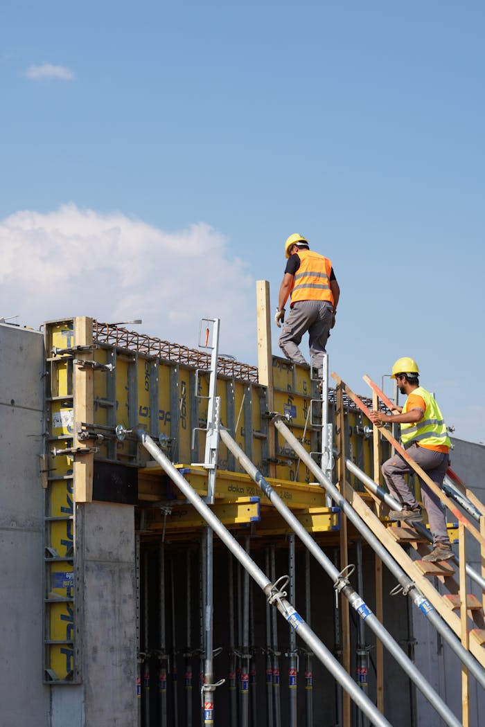 The Art of Drawing Readers In: Your attractive post title goes here Two construction workers building a structure, embodying teamwork and safety under a clear blue sky.